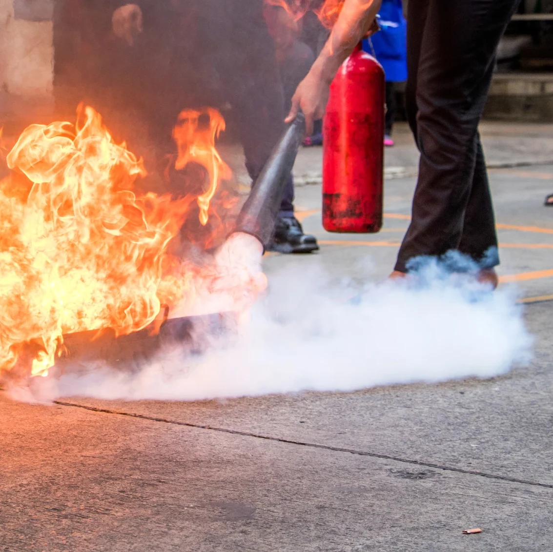 Skilled professionals using CO2 fire extinguishers to safely extinguish a controlled fire during a training session at FC Fire Prevention.